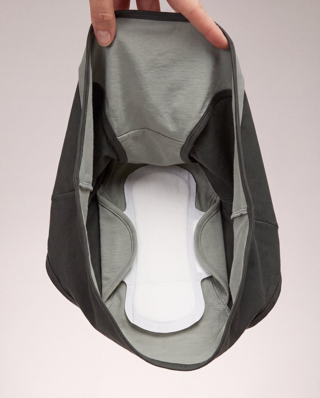 NEO-FORM briefs held open, showing a pad with its wings tucked beneath the inner sage flaps and its surface uncovered
